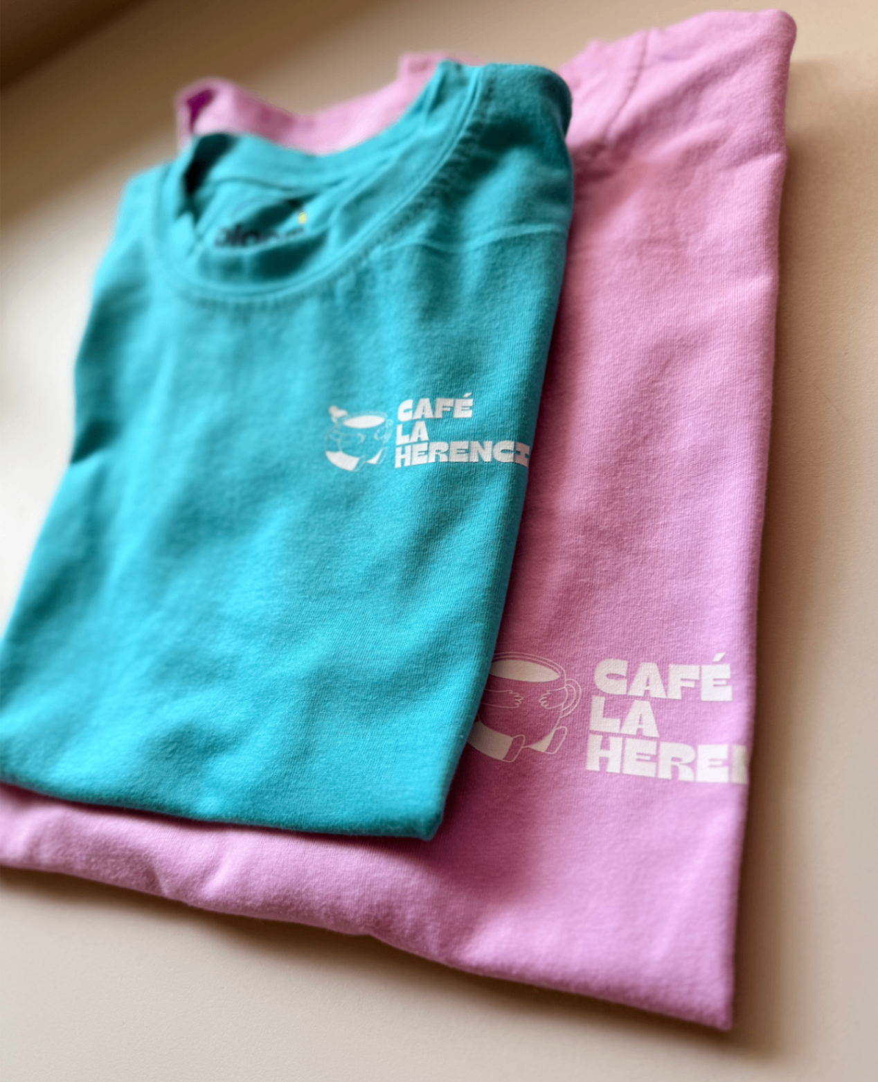 Camisetas Café La Herencia turquesa y rosa